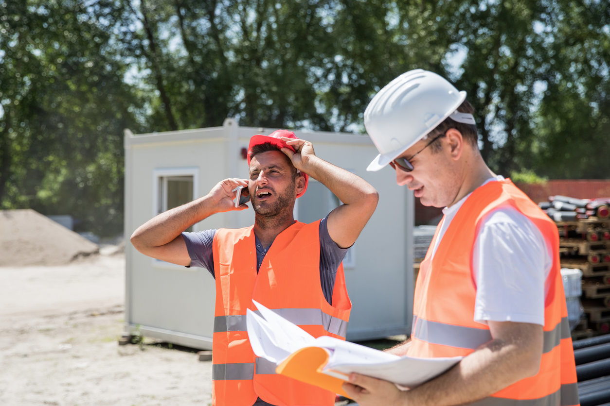 Solutions for Managing Construction Inefficiencies | B3 Software, Custom software for Construction Companies Two construction workers are trying to solve a construction job over the phone.